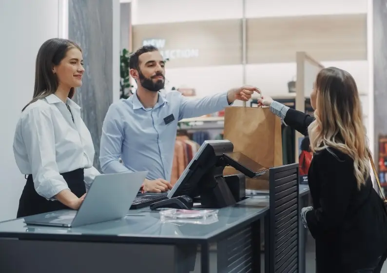A customer receiving a bag containing something she purchased at a store from the cashier